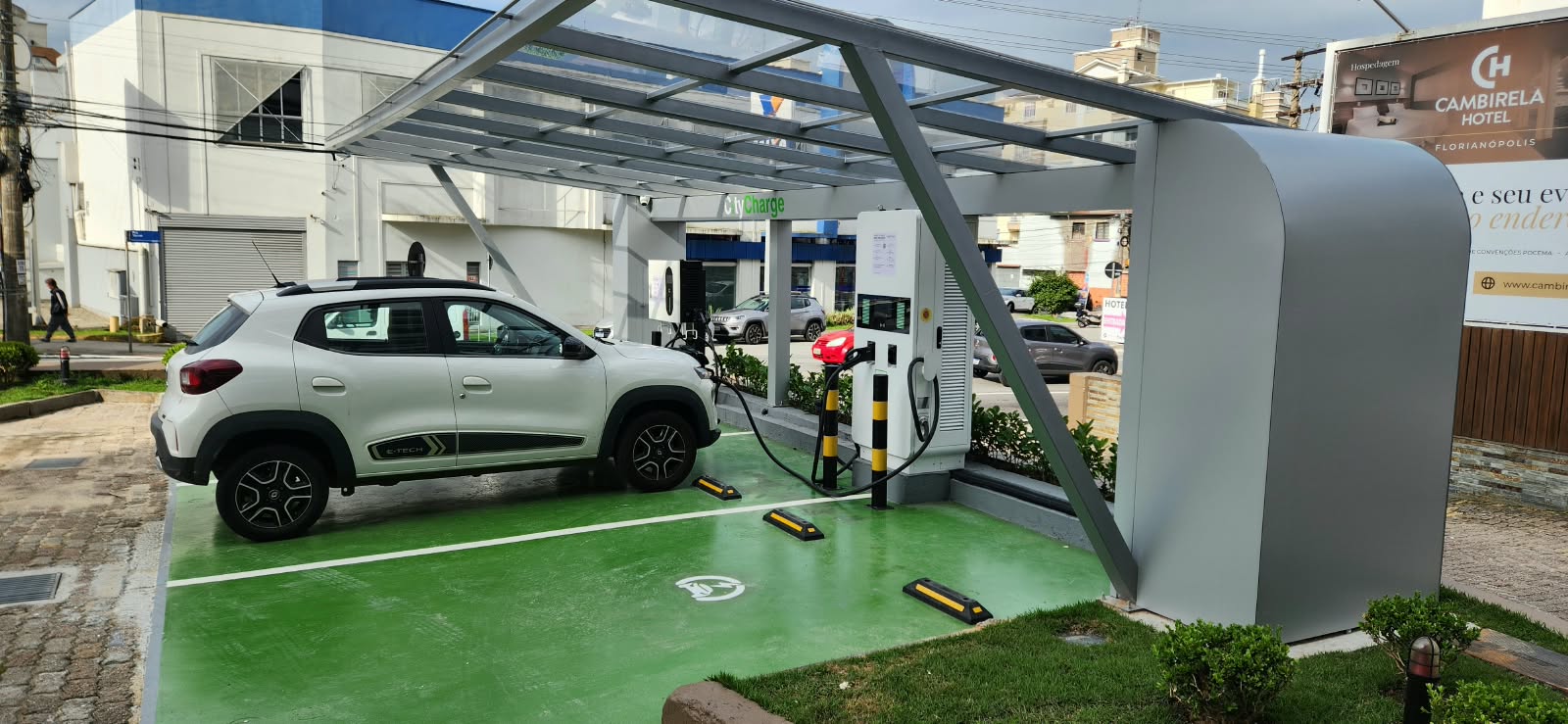 Estação de recarga em operação em Florianópolis, com um veículo elétrico carregando sob a cobertura